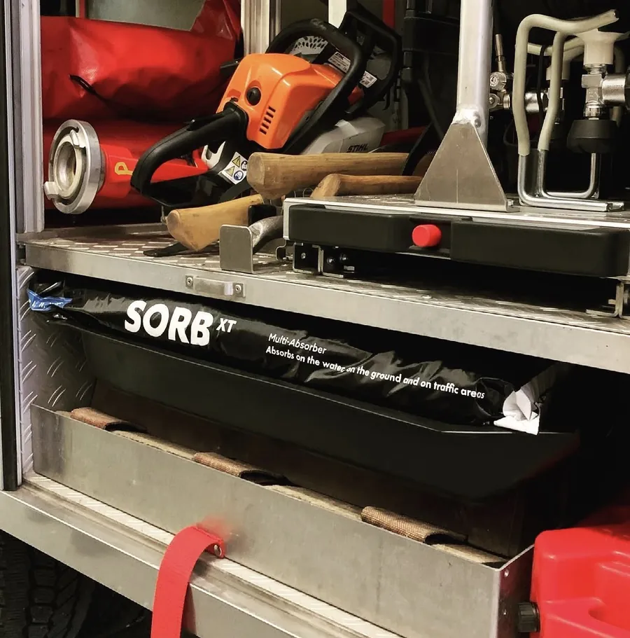 Vrece sorbentu SORB®XT v úložnom priestore hasičského vozidla vedľa motorovej píly a sekier